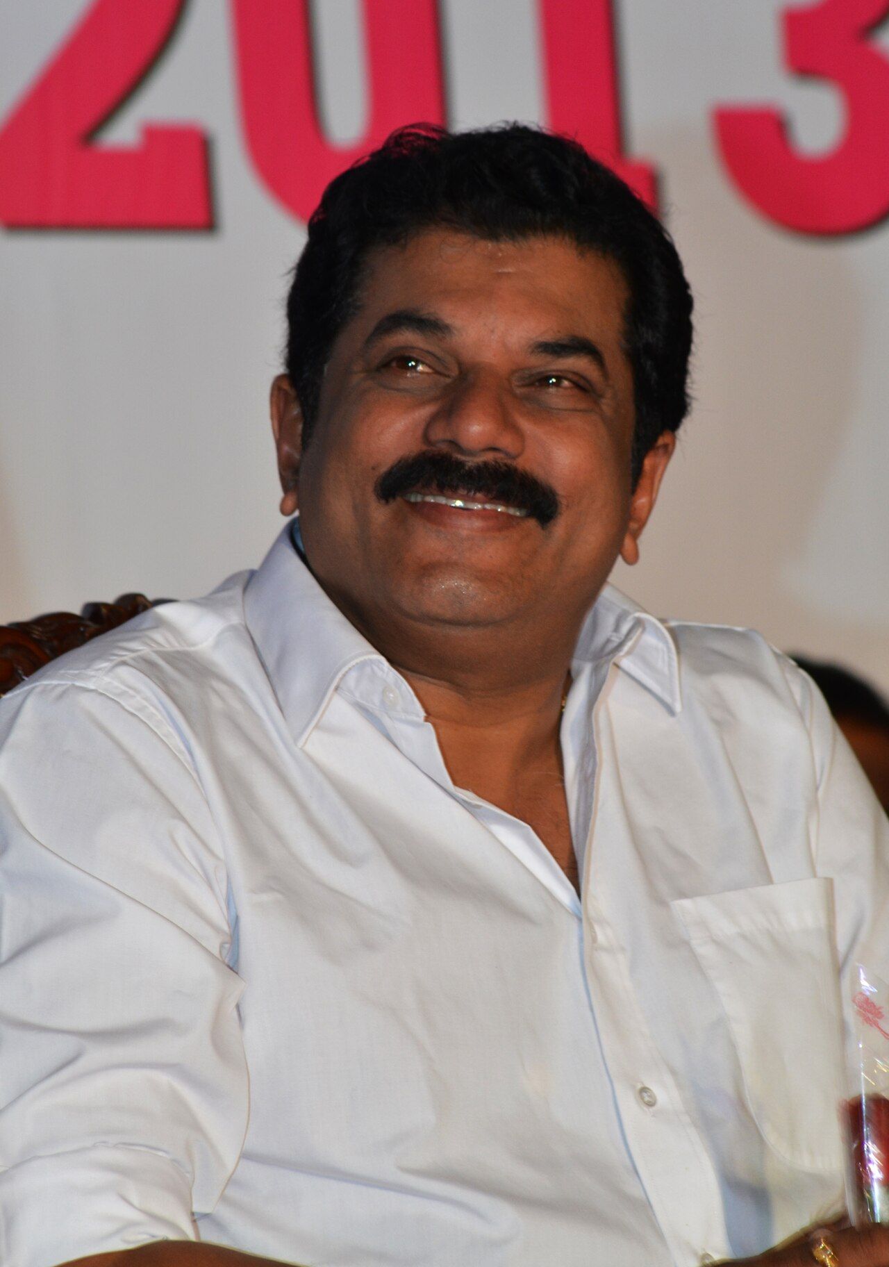 Mukesh in a white shirt seated at an event, portrait