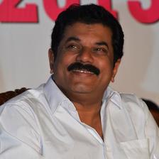 Mukesh in a white shirt seated at an event, portrait