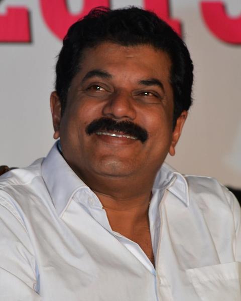 Mukesh in a white shirt seated at an event, portrait