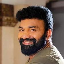 Kottayam Nazeer with a beard in an olive shirt, smiling portrait