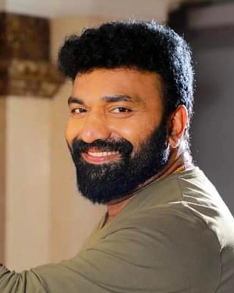 Kottayam Nazeer with a beard in an olive shirt, smiling portrait
