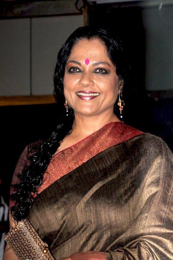 Tanvi Azmi smiling in a brown silk sari with a red border at an event