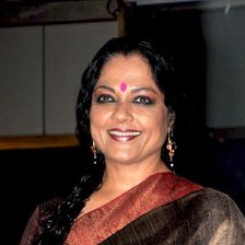 Tanvi Azmi smiling in a brown silk sari with a red border at an event