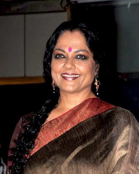 Tanvi Azmi smiling in a brown silk sari with a red border at an event