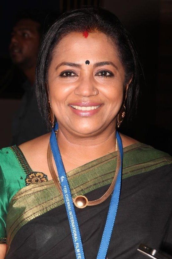 Poornima Bhagyaraj smiling in a green saree with a lanyard
