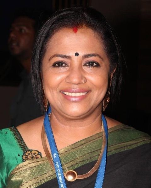 Poornima Bhagyaraj smiling in a green saree with a lanyard