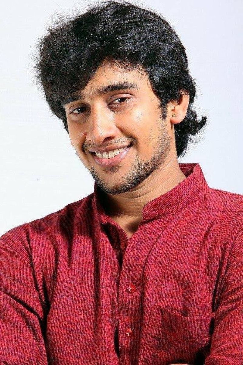 Dhruvan smiling in a maroon shirt against a white background