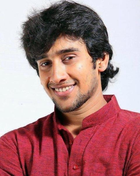 Dhruvan smiling in a maroon shirt against a white background