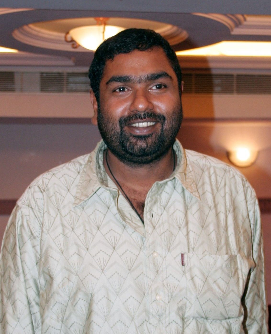 Amal Neerad smiling in a light shirt in a hotel lobby