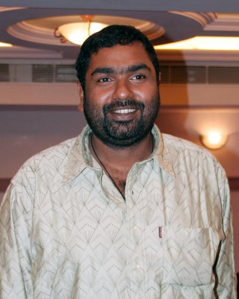 Amal Neerad smiling in a light shirt in a hotel lobby