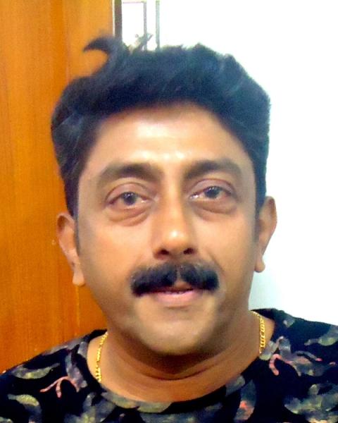 Ashokan with a moustache in a dark printed shirt, close-up portrait