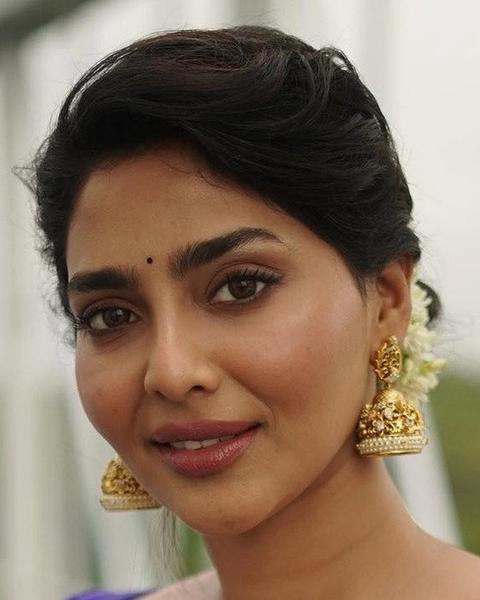 Aishwarya Lekshmi smiling in gold jhumka earrings, close-up portrait