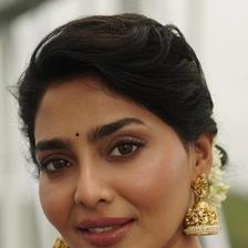 Aishwarya Lekshmi smiling in gold jhumka earrings, close-up portrait