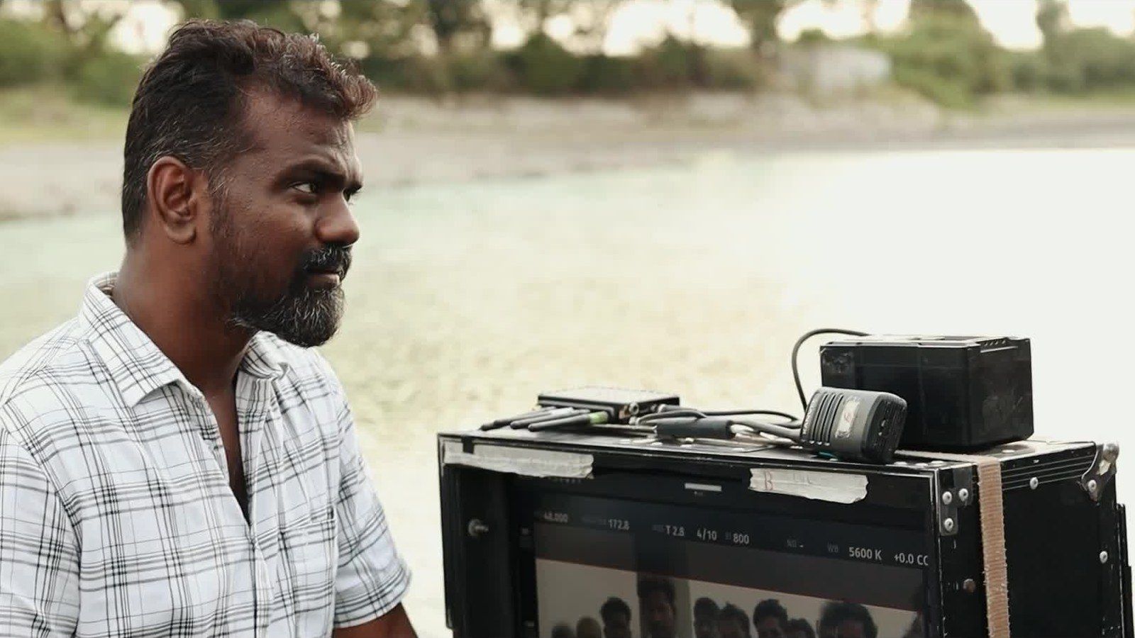 Director Rajkumar Periasamy beside a monitor on the OM set by the water