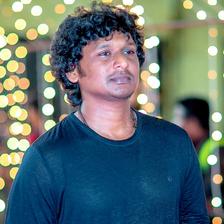 Lokesh Kanagaraj in a blue T-shirt in front of string lights