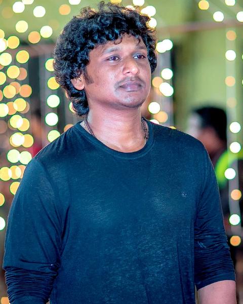 Lokesh Kanagaraj in a blue T-shirt in front of string lights
