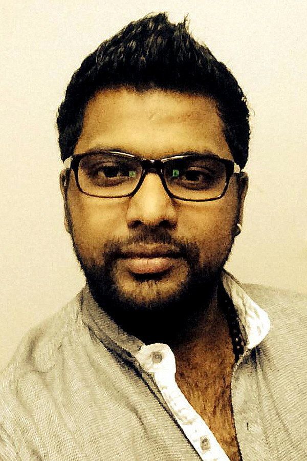 Ullas Chemban with a beard and dark-rimmed glasses in a beige collarless shirt, head-and-shoulders portrait