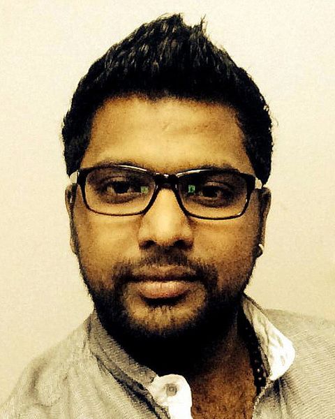 Ullas Chemban with a beard and dark-rimmed glasses in a beige collarless shirt, head-and-shoulders portrait