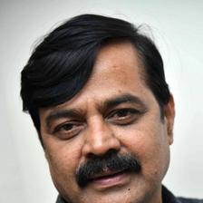 Achyuth Kumar with a moustache in a dark checked shirt, close-up portrait