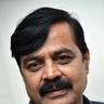 Achyuth Kumar with a moustache in a dark checked shirt, close-up portrait