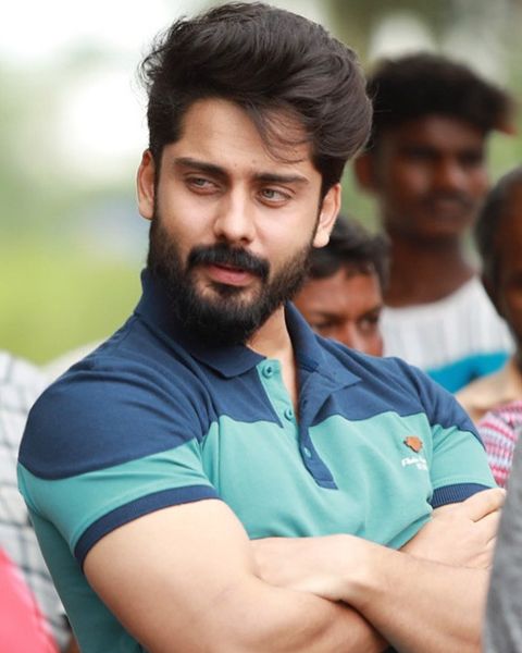Roshan Basheer with a full beard, in a teal and navy polo shirt, arms folded outdoors