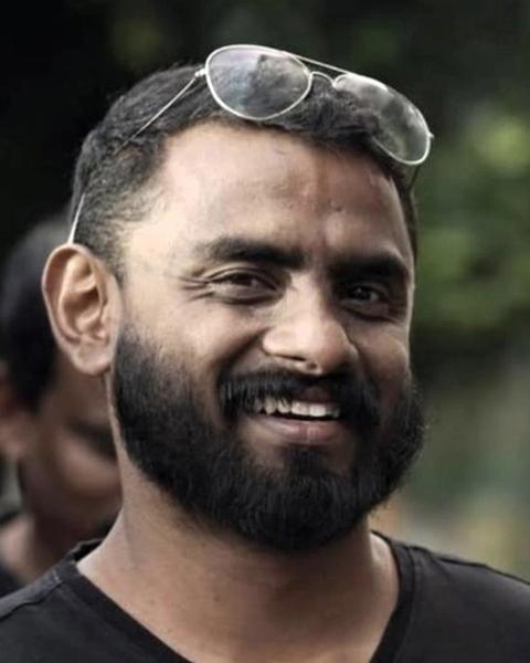 Jithin K Jose with a beard and sunglasses on his head in a black T-shirt, smiling