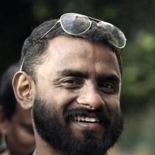 Jithin K Jose with a beard and sunglasses on his head in a black T-shirt, smiling