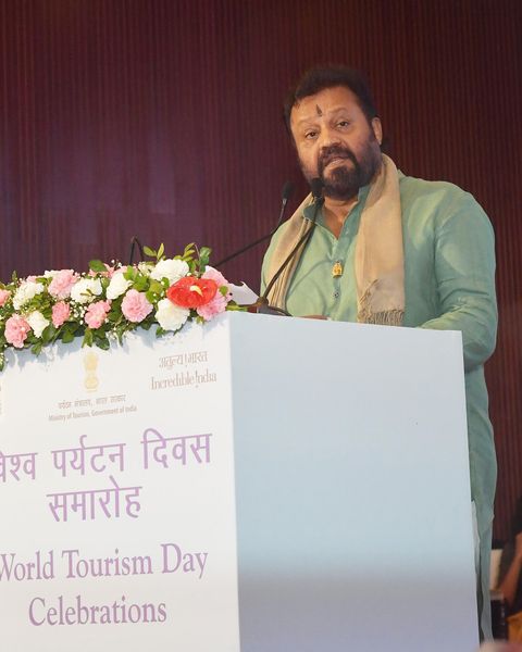 Suresh Gopi in a green kurta and shawl speaking at a World Tourism Day lectern