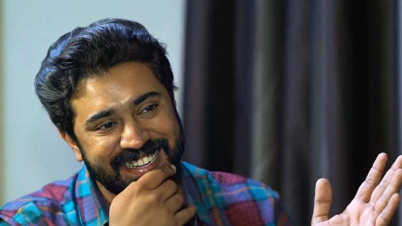Nivin Pauly, lead of Bethlehem Kudumba Unit, smiling in a check shirt