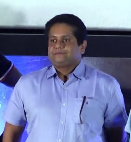 Jeethu Joseph in a light blue shirt at an event stage
