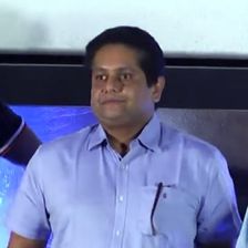 Jeethu Joseph in a light blue shirt at an event stage