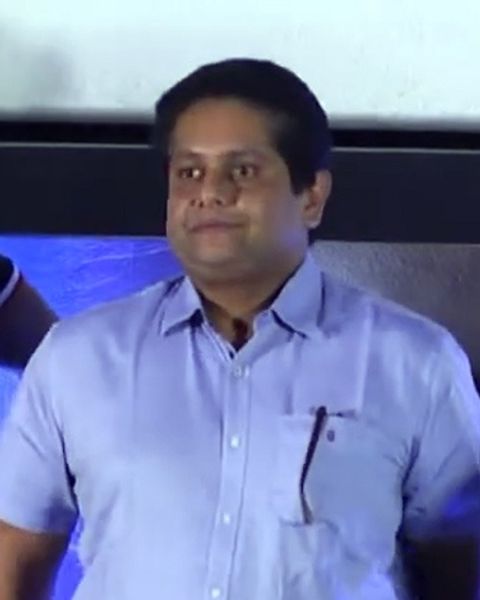 Jeethu Joseph in a light blue shirt at an event stage