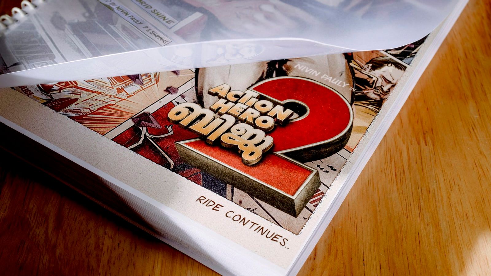 Action Hero Biju 2 announcement poster showing the title on a script cover with Nivin Pauly's name