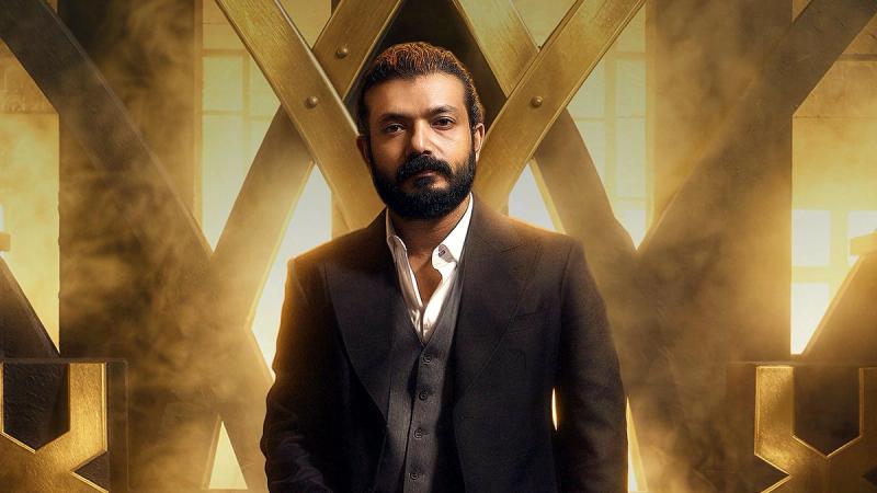 Sreenath Bhasi in a dark suit before a golden throne on the Orijinal Gulf release poster