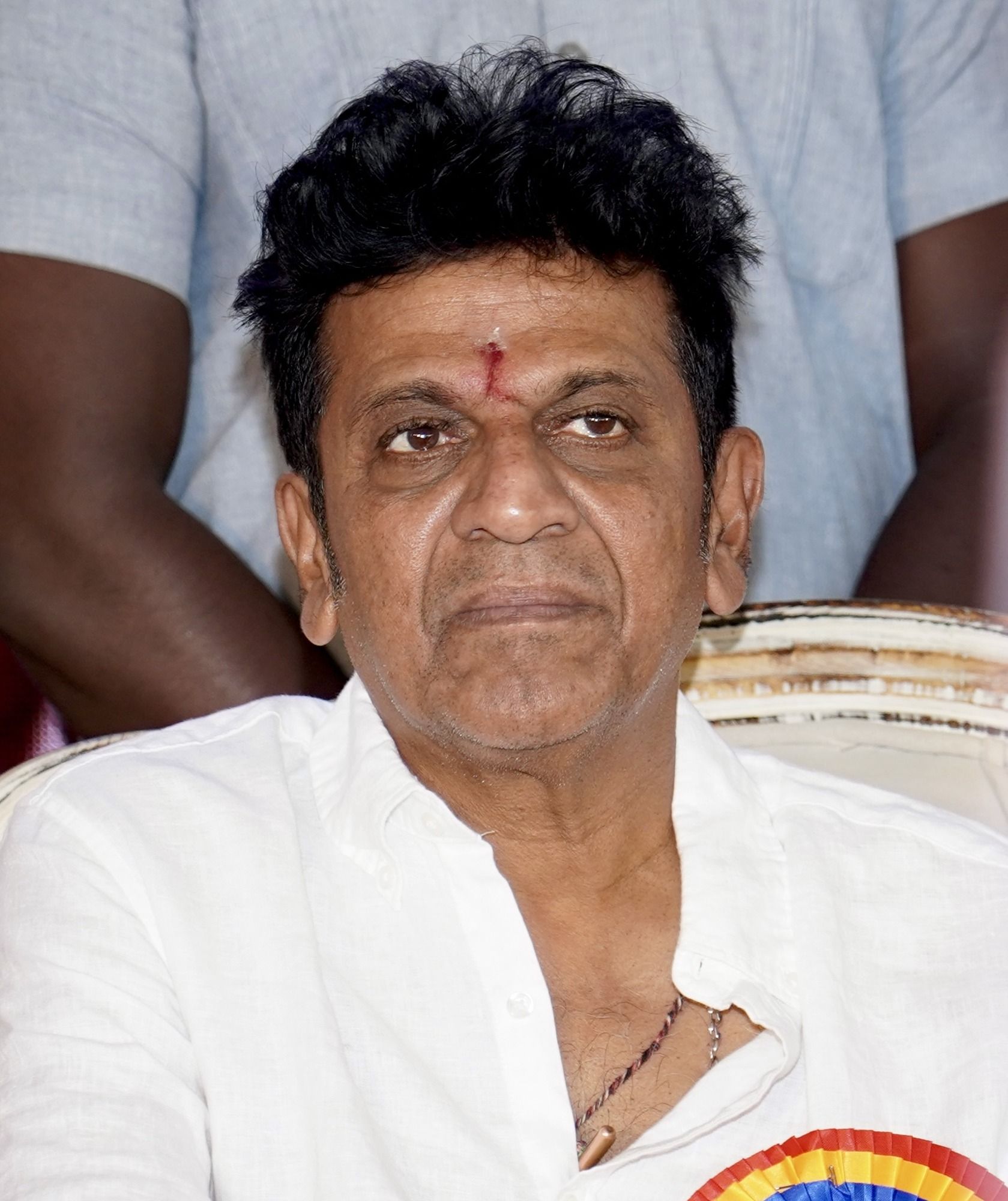 Shiva Rajkumar in a white shirt at an indoor event