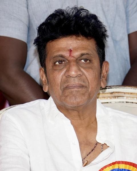 Shiva Rajkumar in a white shirt at an indoor event