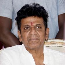 Shiva Rajkumar in a white shirt at an indoor event