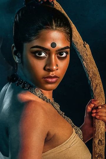 Asthikkari first look showing Sakhi Satya in character, with a black bindi and beaded necklace, gripping a curved wooden staff against a smoky dark background