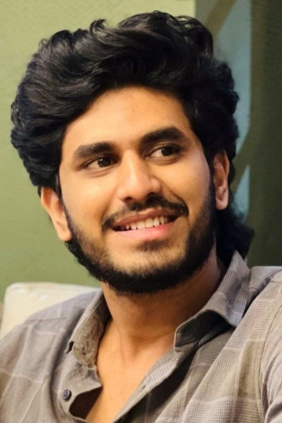 Nihal Nizam smiling and looking to the side in a grey checked shirt, head-and-shoulders portrait