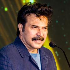 Mammootty speaking at a microphone in a blue denim jacket, 2022