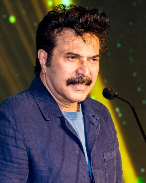 Mammootty speaking at a microphone in a blue denim jacket, 2022
