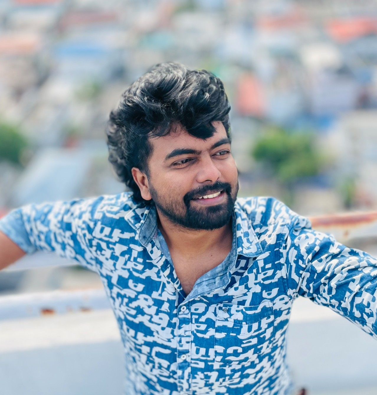 Dinoy Paulose in a blue printed shirt on a rooftop overlooking the city