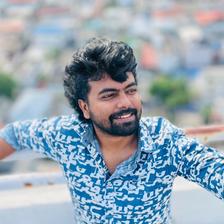 Dinoy Paulose in a blue printed shirt on a rooftop overlooking the city