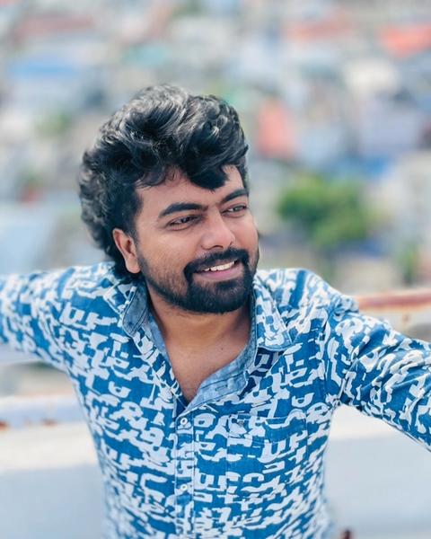 Dinoy Paulose in a blue printed shirt on a rooftop overlooking the city