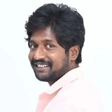 Suhas smiling in a pink shirt against a light background
