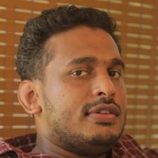 Girish A. D. in a checked shirt glancing to the side, close-up