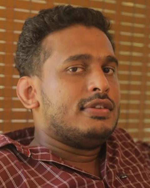 Girish A. D. in a checked shirt glancing to the side, close-up