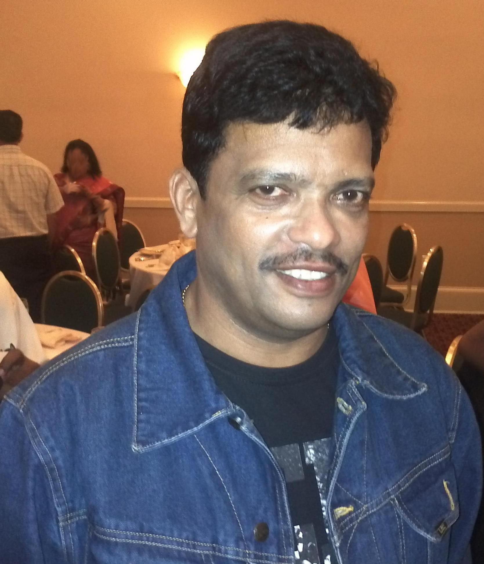 Jagadish smiling in a denim jacket at an indoor event