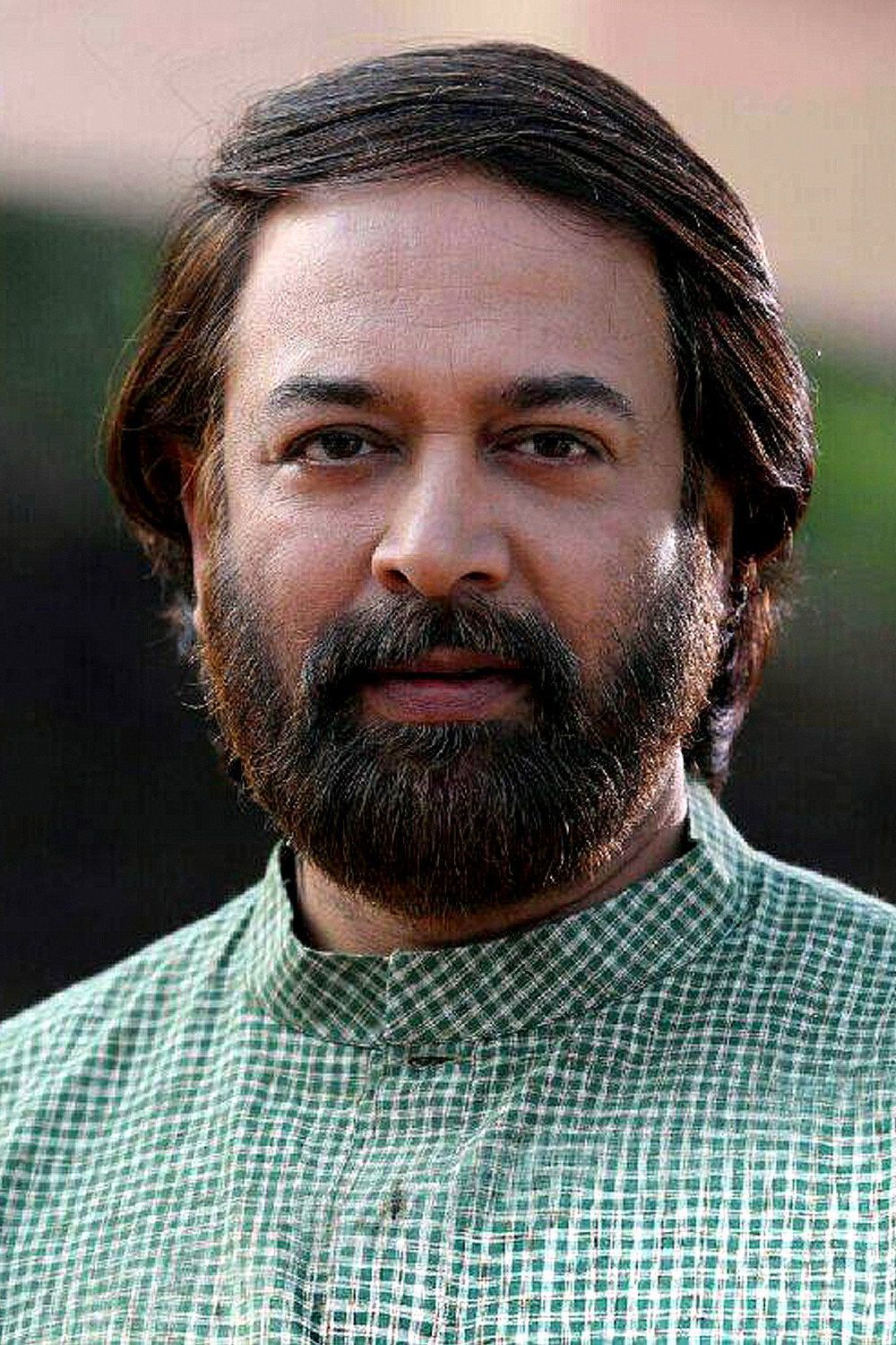 Madhupal with a beard in a green checked shirt, head-and-shoulders portrait