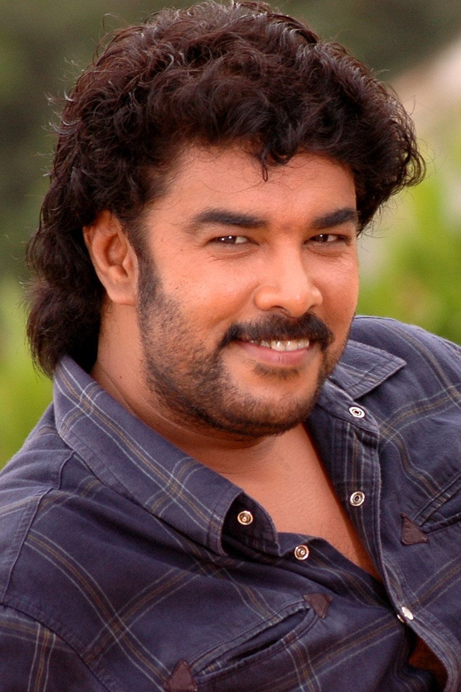 Sundar C with curly hair and a moustache in a dark shirt, half-length portrait